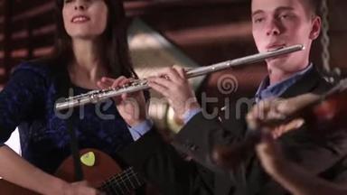 两个人音乐家复制音乐。 一个穿着夹克和衬衫的男人吹笛子，一个穿着蓝色裙子的漂亮黑发女人吹笛子